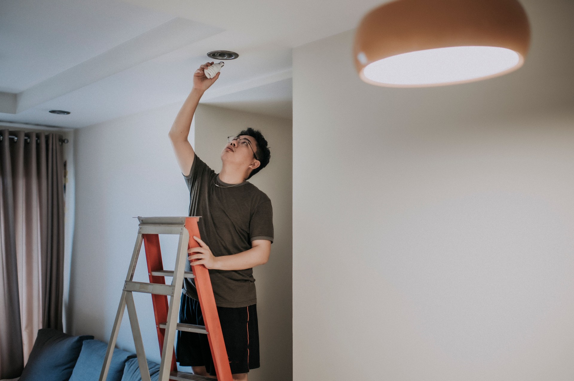 une ampoule chinoise chinoise asiatique de changement d’homme dans le salon, la maison d’appartement