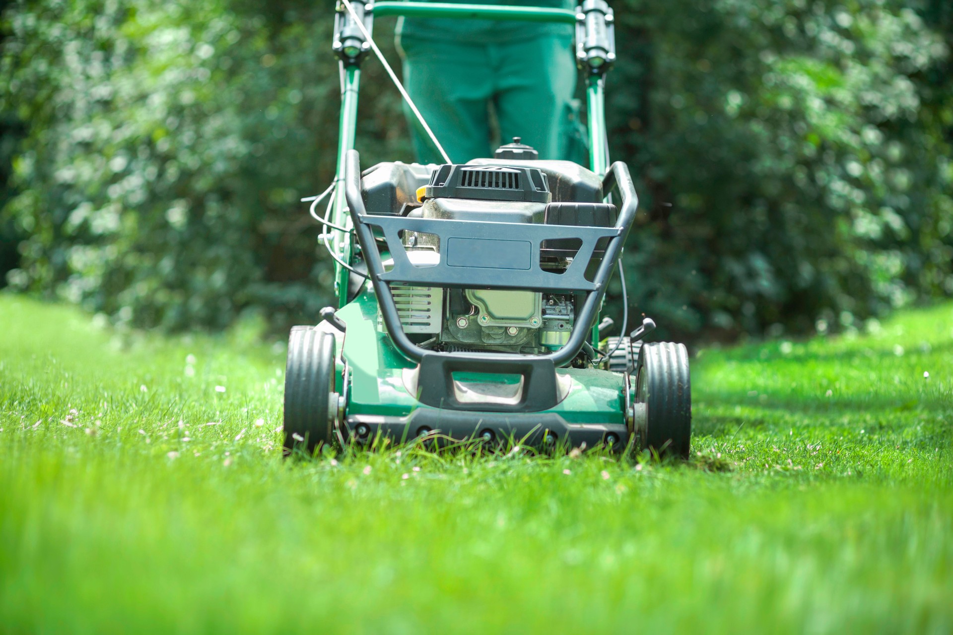 Man mowing a green grass lawn.